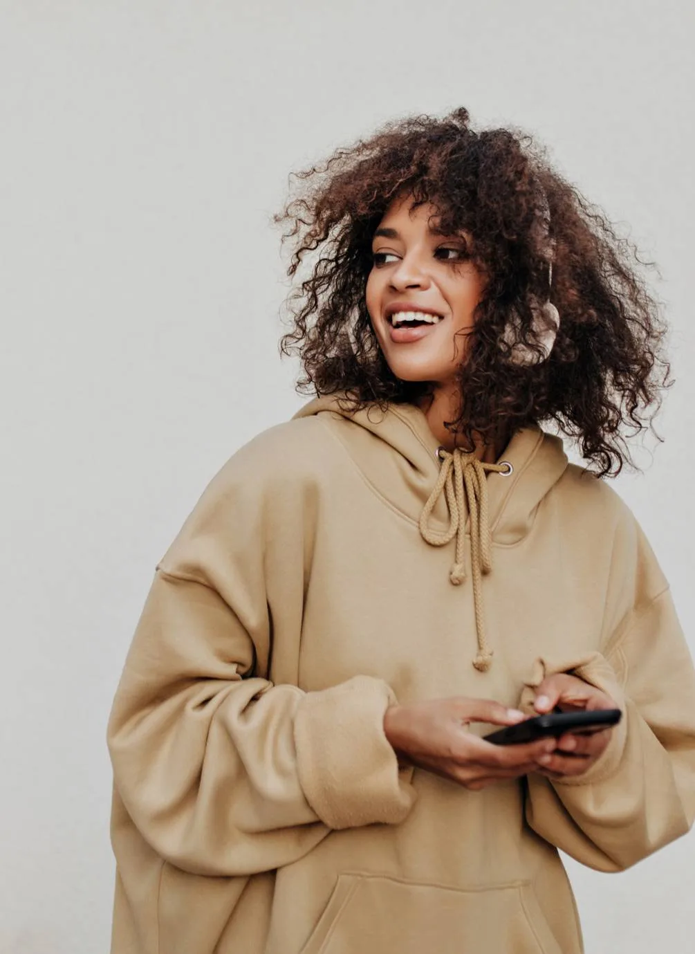 Woman holding a smartphone and looking to the side.