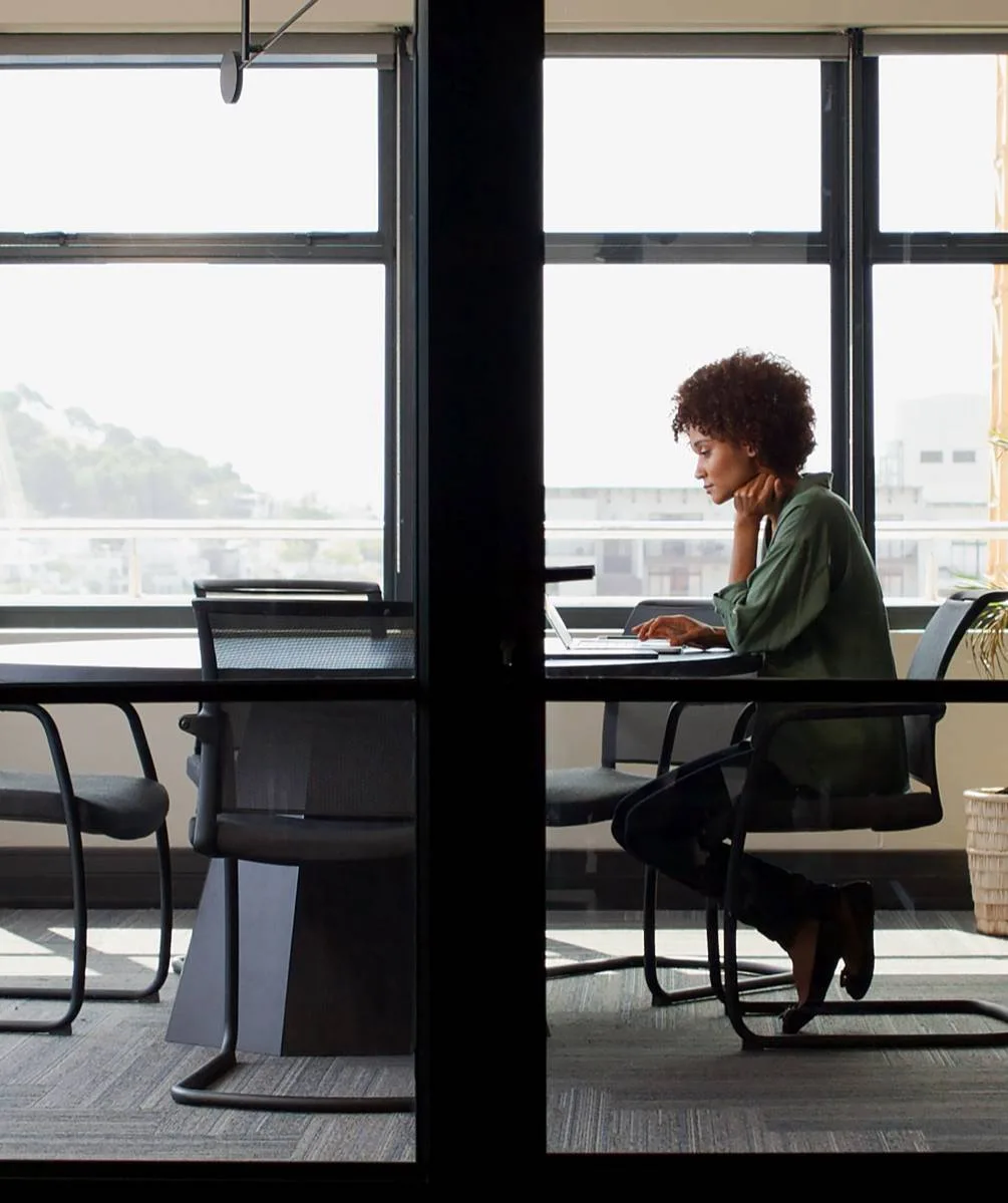 Person working at a desk in a glass-walled office.