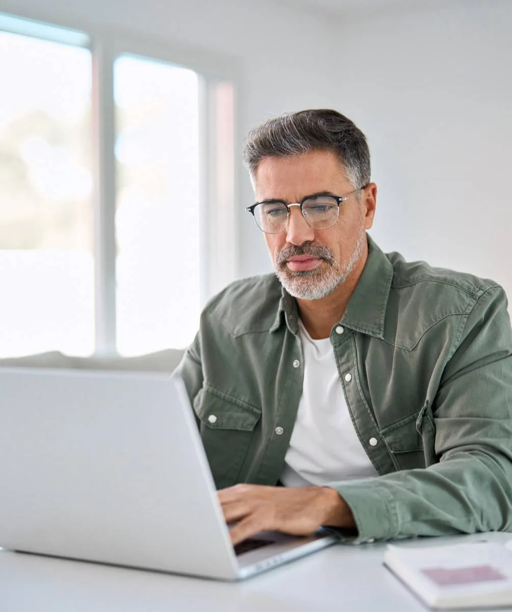 Man wearing glasses working on a laptop.
