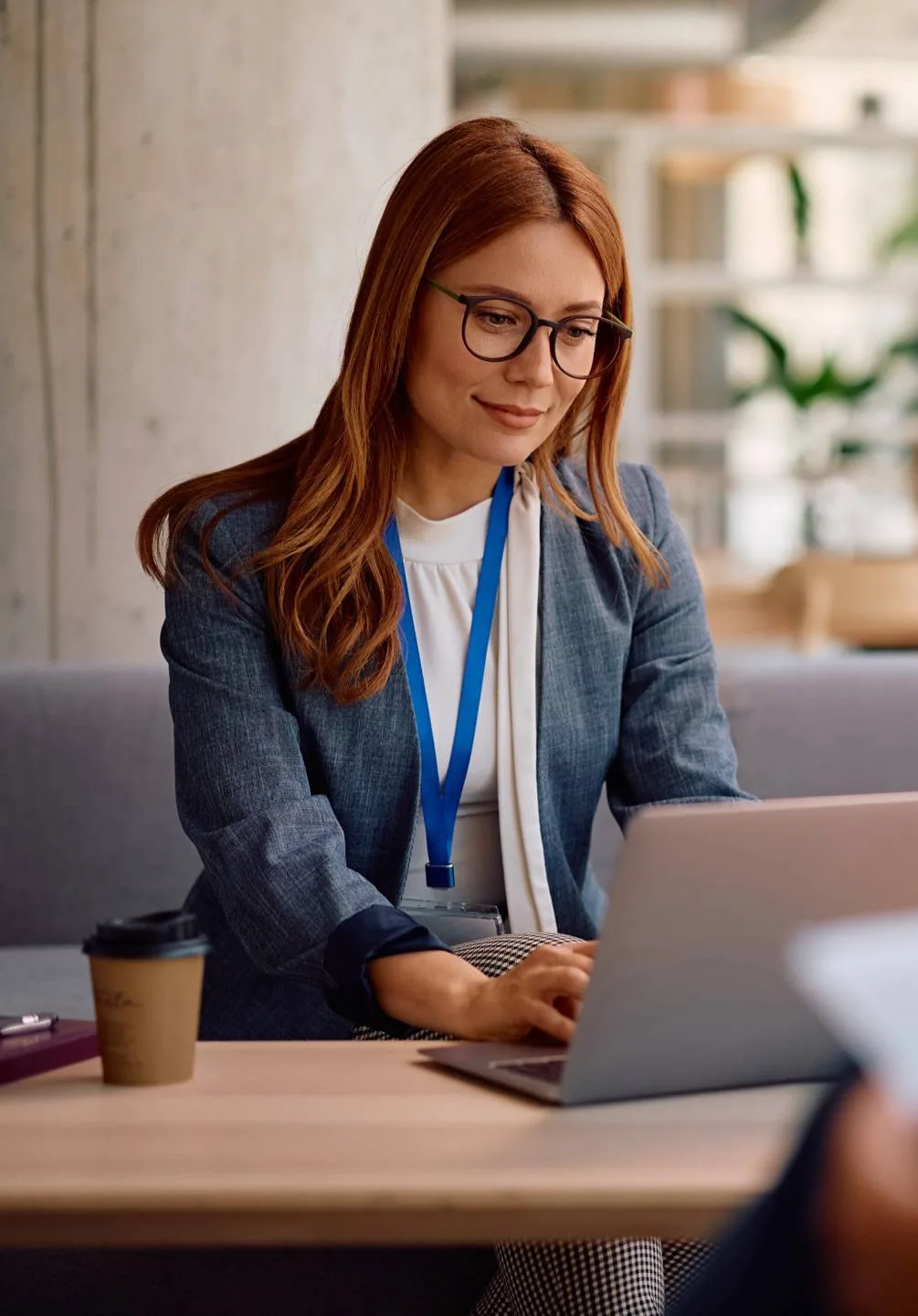 Woman wearing glasses working on a laptop in an office.