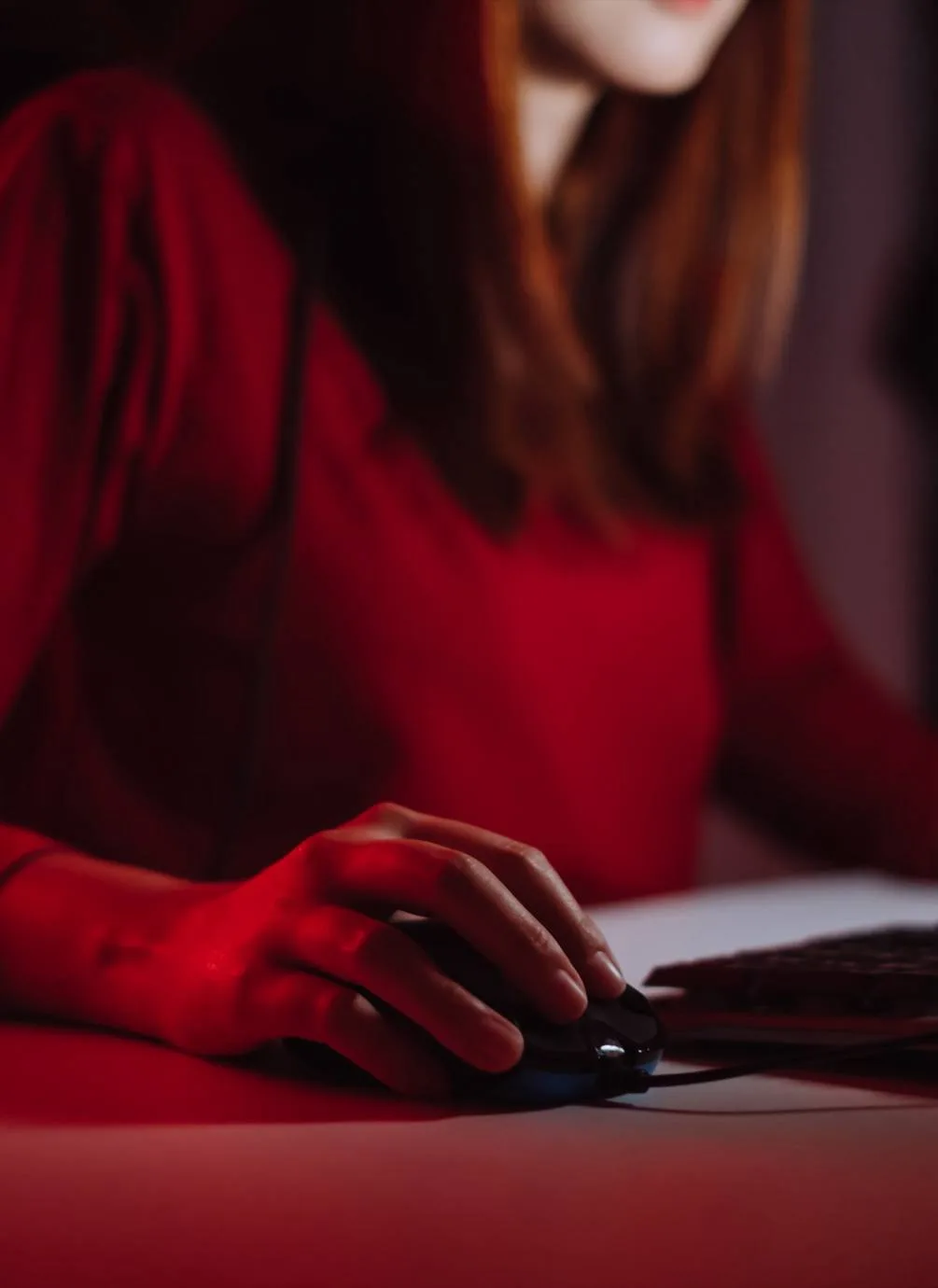 Person using a keyboard in a room illuminated by red light.