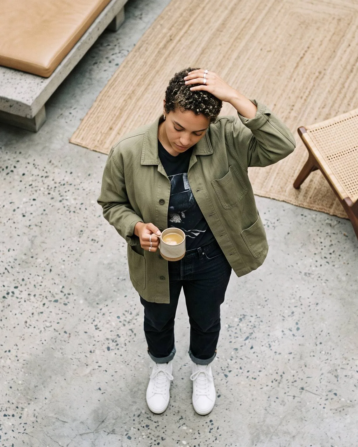 Person holding a coffee cup while standing beside a table.