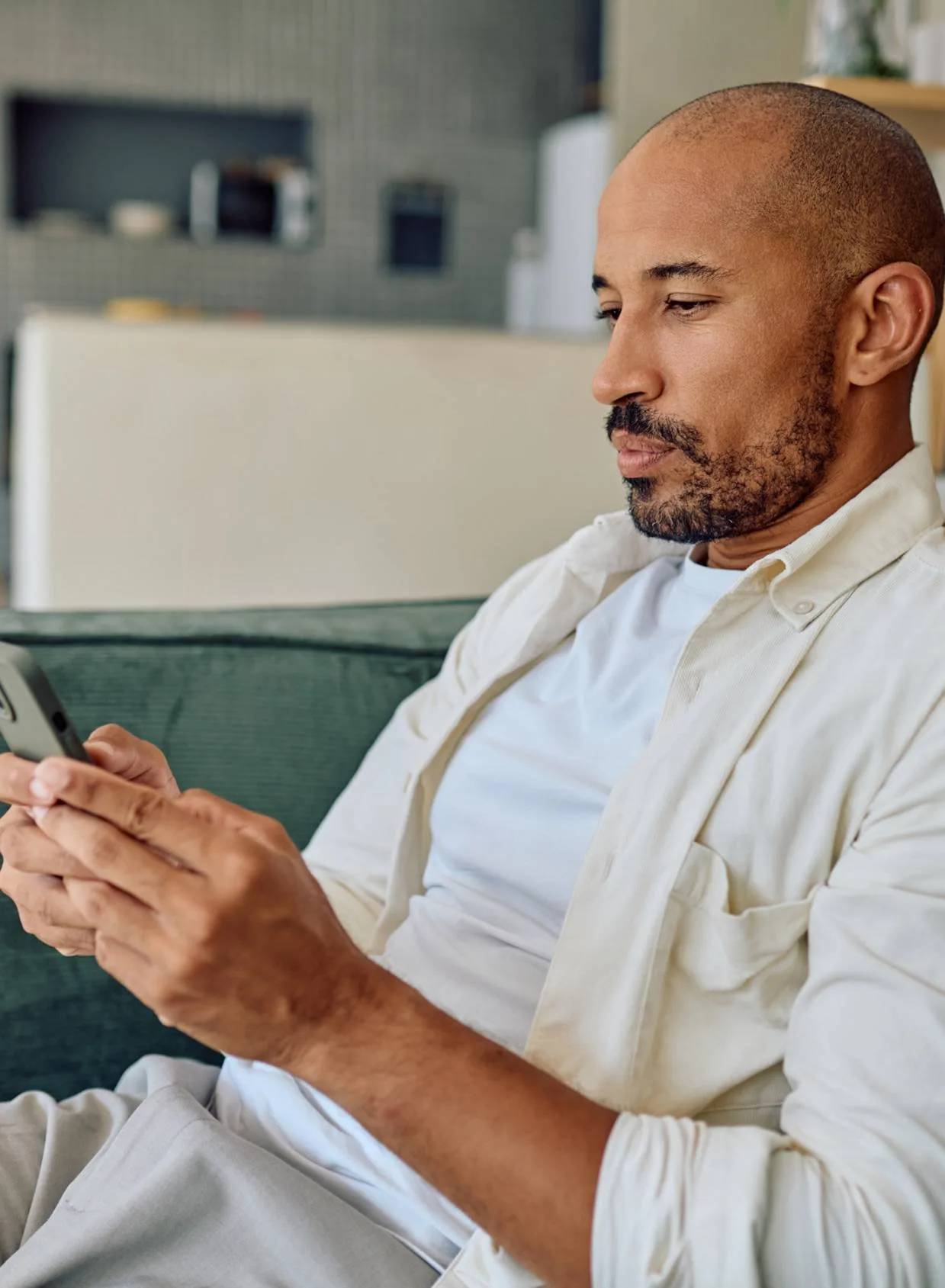 Man sitting on a sofa and checking his smartphone.